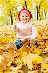 Laughing kid sits in an autumn park