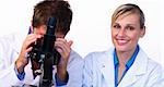 Beautiful woman smiling at the camera and male scientist looking through a microscope