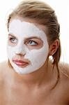 Kosmetik-Maske aus Ton auf dem jungen weiblichen Gesicht