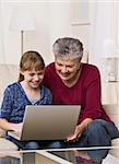 Une grand-mère et petite-fille utilisent un ordinateur portable à la maison. Photo encadrée verticalement.