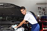 mechanic cleaning car engine and looking at camera