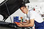 mechanic leaning on bonnet with tester equipment and looking at camera