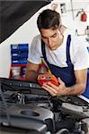 mechanic leaning on bonnet with tester equipment and looking at camera