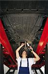 mechanic standing under car engine and holding lamp. Copy space