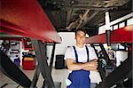 portrait of mechanic standing under car with arms folded. Copy space