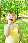 Preschool girl eating lollipop in a city park