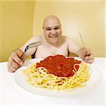 An overweight man enjoying a plate of spaghetti.  Shot with fish-eye lens.  Focus is on the face.