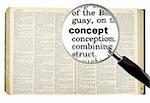 A magnifying glass on the word CONCEPT on a dictionary. Isolated on white.