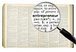 A magnifying glass on the word ENTREPRENEUR on a dictionary. Isolated on white.