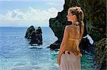 Beautiful brunette with long hair standing on the sand beach overlooking the sea