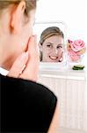 Female model looking into mirror applying cream