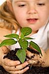 Little girl holding a new plant with soil