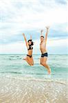 Happy young couple jumping in the sea