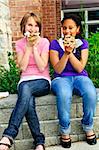 Deux adolescentes s'asseoir et manger des pizzas