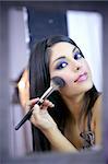 Maquillage de modèle de mode indienne avec la brosse sur le miroir