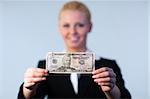 Business woman holding up dollars with camera focus on the dollars