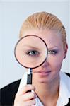 Young Serious Business woman looking through a magnifying Glass