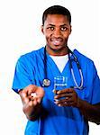 Sympathique médecin africain dans scrubs pilules et verre de l'eau en regardant la caméra