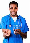 Junge afroamerikanische Arzt in Scrubs – die Anfänger mit Pillen und Glas Wasser in die Kamera Lächeln