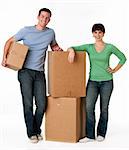 A couple is standing next to moving boxes and they are smiling at the camera.  Vertically framed shot.