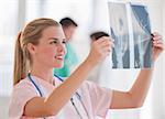 A young doctor is smiling and looking at some x-rays.  Horizontally framed shot.