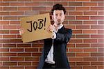 Young businessman standing pleading with sign "Need Job"
