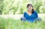happy young woman sitting on grass in park