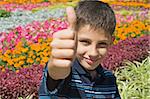 a teen is holding his thumb up sitting in the flowers