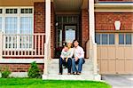 Young family sitting on front steps of house