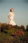 Young beauty woman with suitcase jumping outdoors