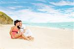 Romantic couple sitting on sand and looking at the sea