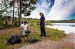 Camping lifestyle - a man and woman setting up a tent by a lake