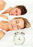 Attractive couple in bed with alarm clock going off