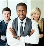 Afro-American businessman with folded arms with his colleagues smiling at the camera