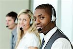 Businesspeople with headsets smiling at the camera at work