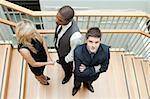 High view of Businessman and businesswoman shaking hands and a man with folded arms on stairs