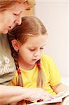 Adorable petite fille lisant un livre avec sa grand-mère