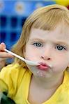 Adorable petite fille blonde manger et faire des gestes avec cuillère