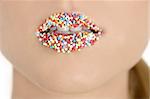 close up of woman lips with multicolored sweet pearls