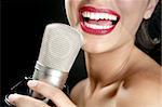 Beautiful woman singing on a vintage microphone on black background