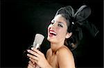 Schöne Frau, die singt auf einem Jahrgang Mikrofon auf schwarzem Hintergrund