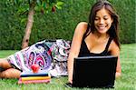 Étudiante avec ordinateur portable dans le parc. Beau sourire race mixte caucasien / asiatique modèle.