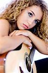 An attractive young teenage woman with an acoustic guitar on white background (shallow depth of field used)