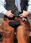 Closeup of cowboy with chaps, guns and leather belt