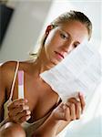 blonde woman holding pregnancy test and reading information.