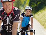 Senior man and young woman on road bike. Focus on background