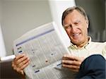 Senior man reading stock listings and smiling. Copy space