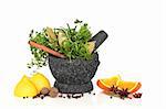 Herb leaf selection in a granite mortar with pestle and spices, with orange and lemon halves, over white background.