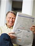 Senior man reading stock listings and smiling