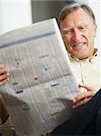 Senior man reading stock listings and smiling